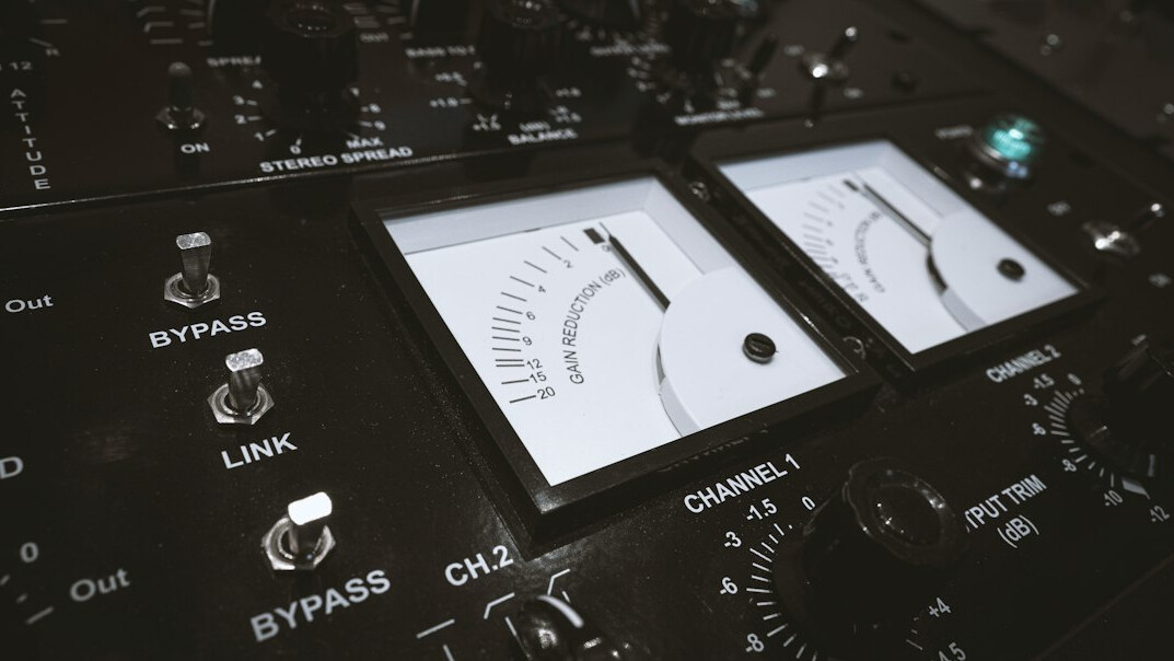 Audio mixing console with sliders and waveform meters