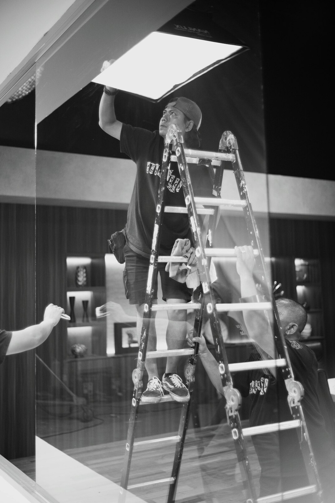 Lighting technician adjusting a studio fresnel light on a ladder
